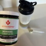 A hand holds a container of Morning Complete by ActivatedYou.