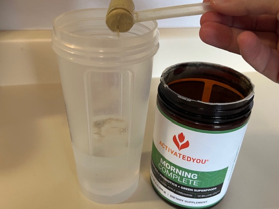 Pouring a scoop of Morning Complete into a shaker cup.