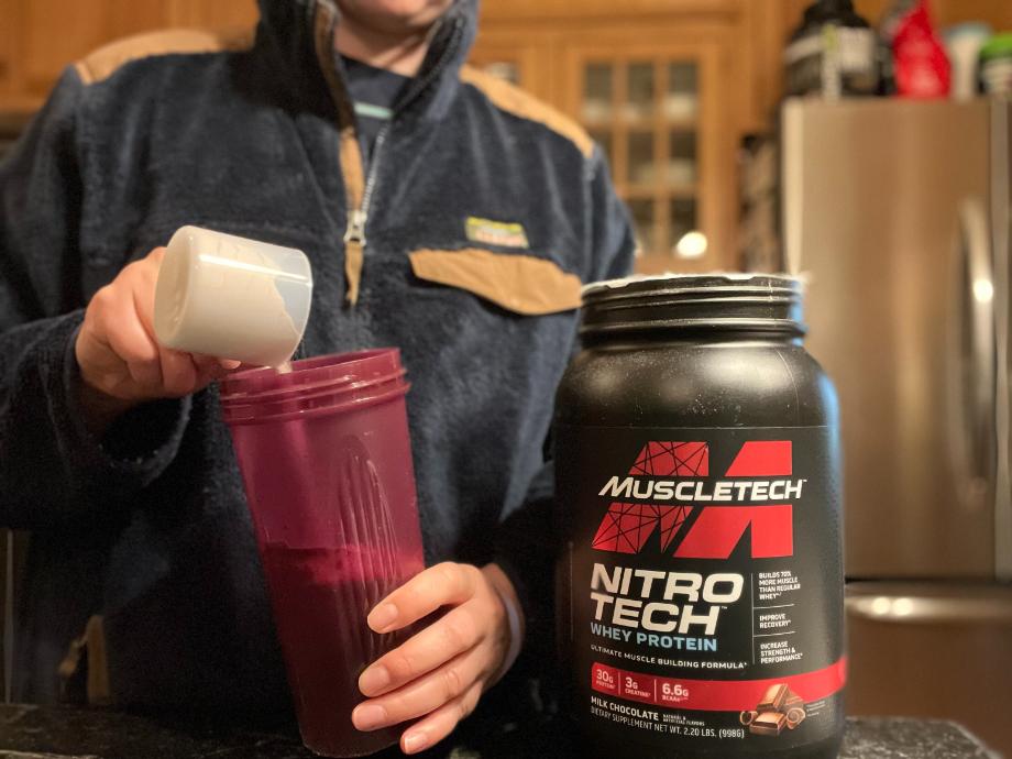 A person makes a shake with MuscleTech Nitro Tech protein powder.