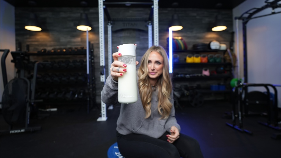 A person holds up a freshly-mixed Naked Casein shake.