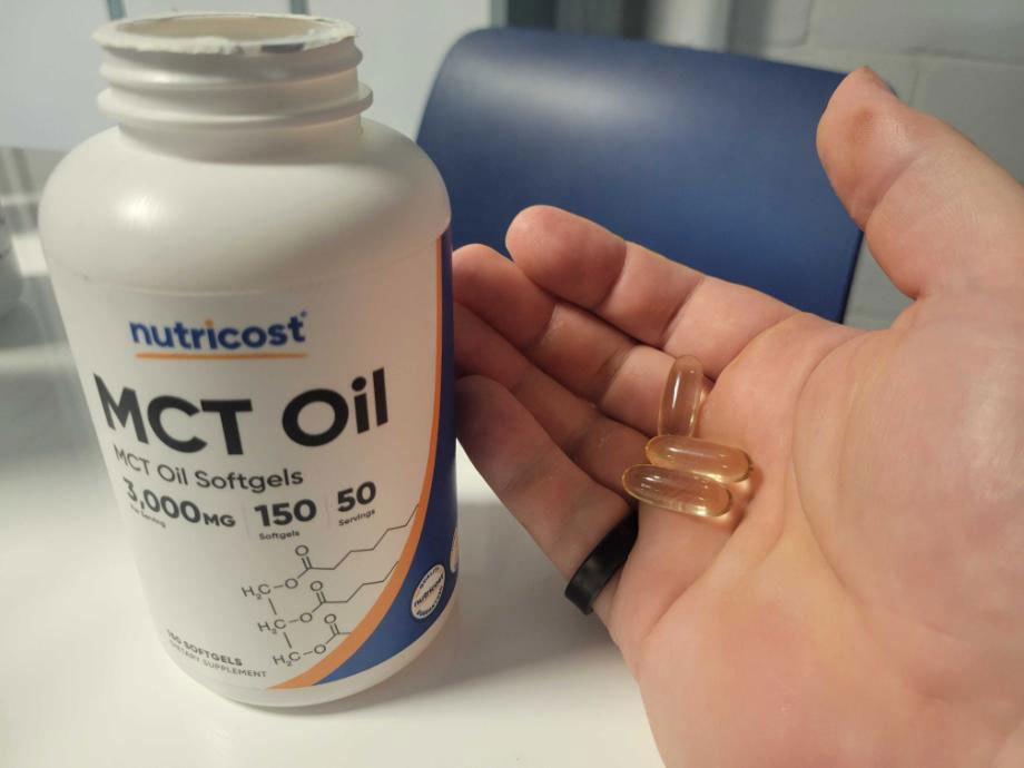 A close look at Nutricost MCT Oil capsules in a person's hand.