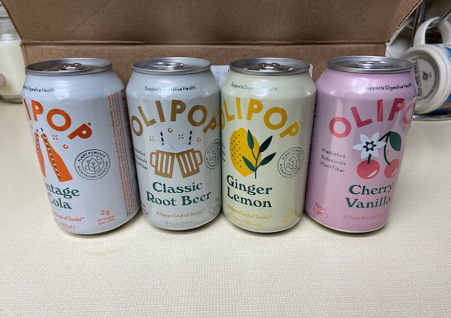 Vintage Cola, Classic Root Beer, Ginger Lemon, and Cherry Vanilla flavors of OLIPOP lined up next to each other