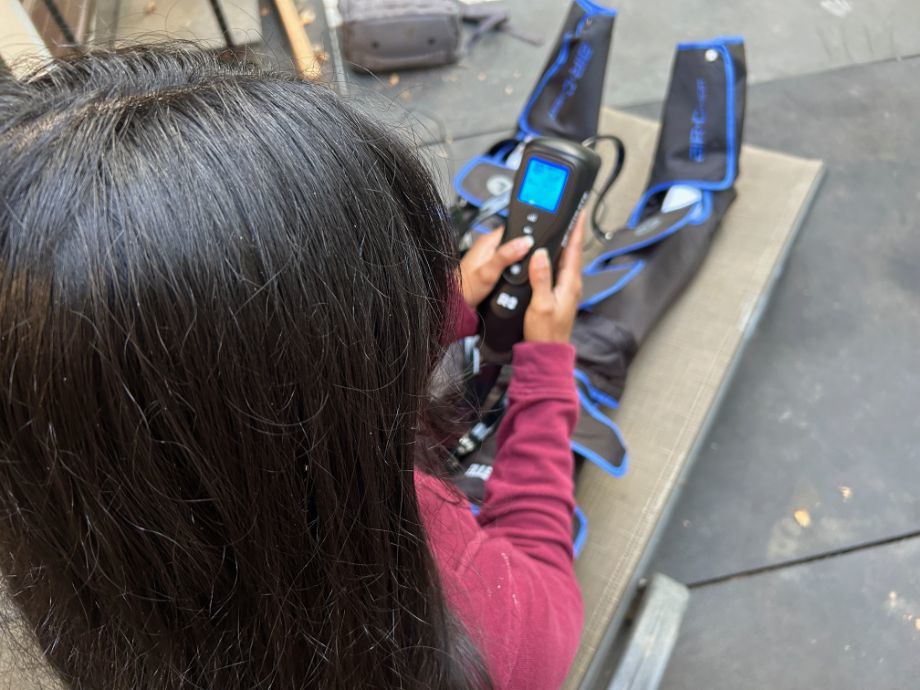 Looking over the shoulder of someone adjusting a pair of Reathlete Air-C compression boots