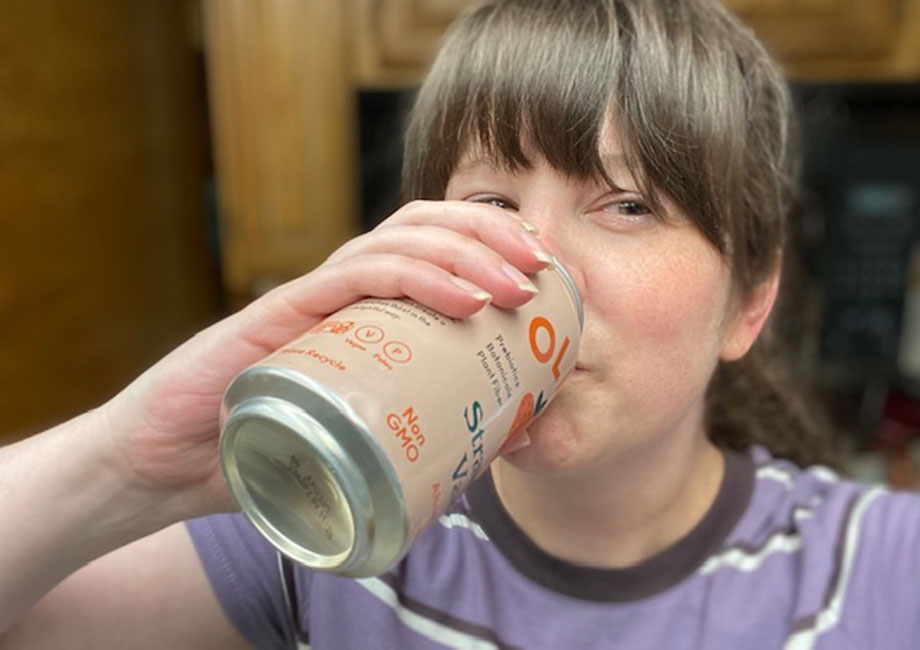 Woman drinking OLIPOP in the Strawberry Vanilla flavor