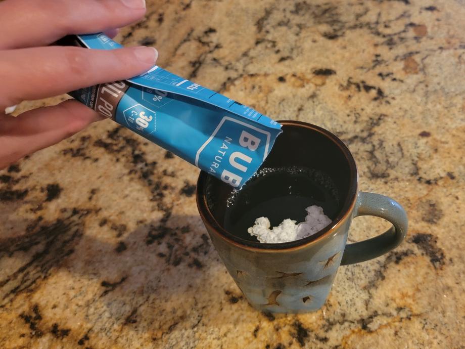 Pouring a pouch of BUBS MCT Oil powder into a cup of coffee