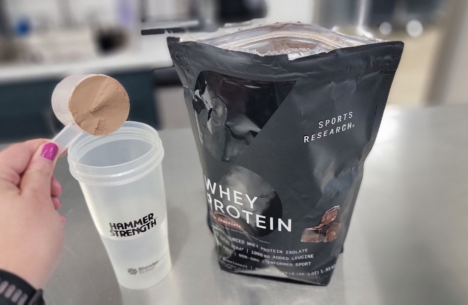 Pouring Sports Research Whey Protein Isolate into a bottle of water