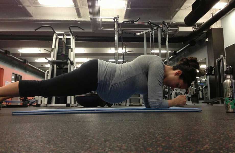 Kate doing a plank in a gym while pregnant