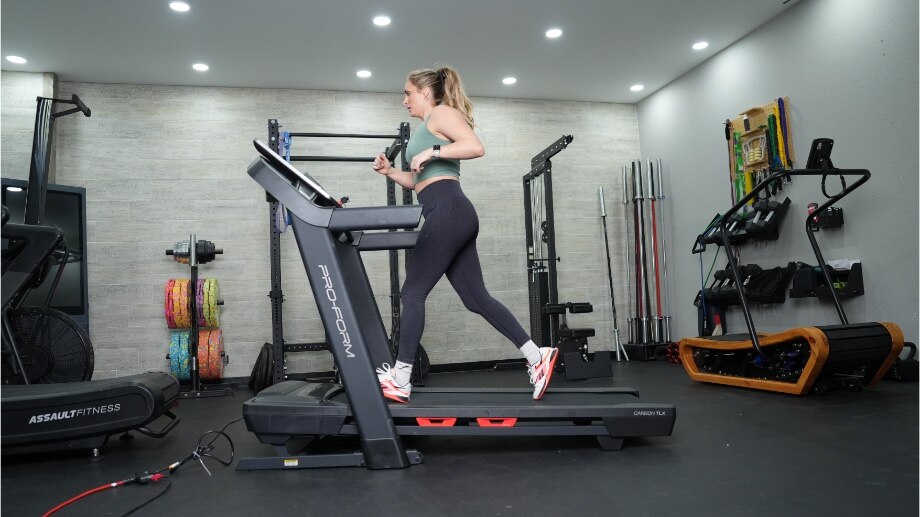 A full side view of a woman jogging on the ProForm Carbon TLX treadmill