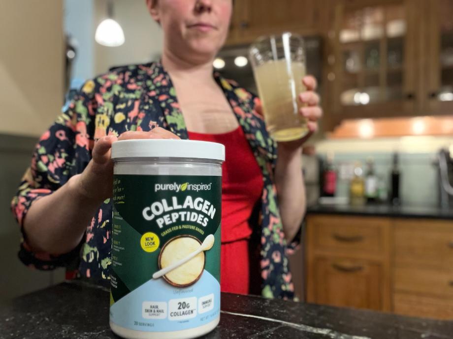 A woman considers a glass of Purely Inspired Collagen Peptides.