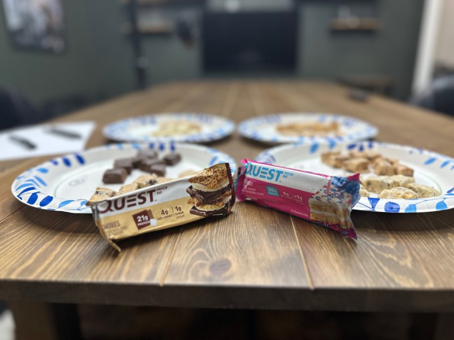 Two Quest Bars are staged in front of plates with sample cubes of different flavors.