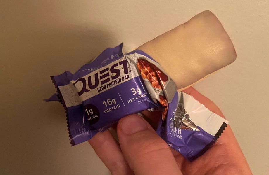 A person's hand holding a Quest Hero protein bar