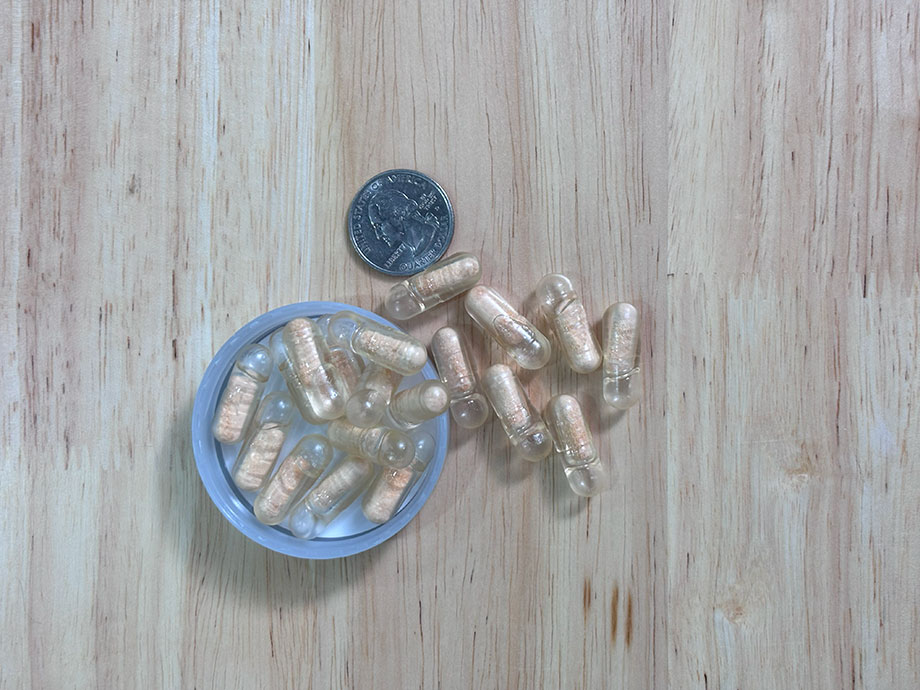 Some Ritual Synbiotic capsules are shown next to a USD quarter for size comparison.