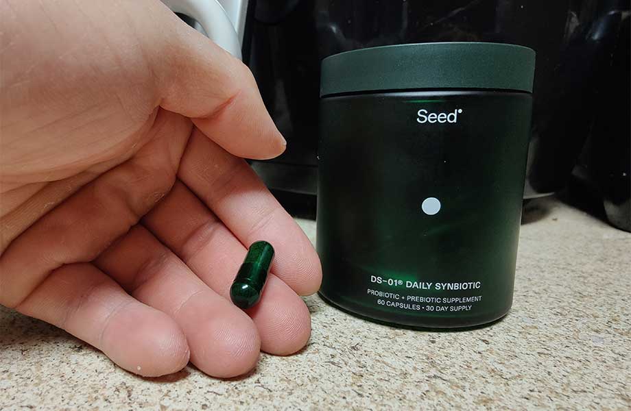 Our tester holds a Seed probiotic capsule next to the container