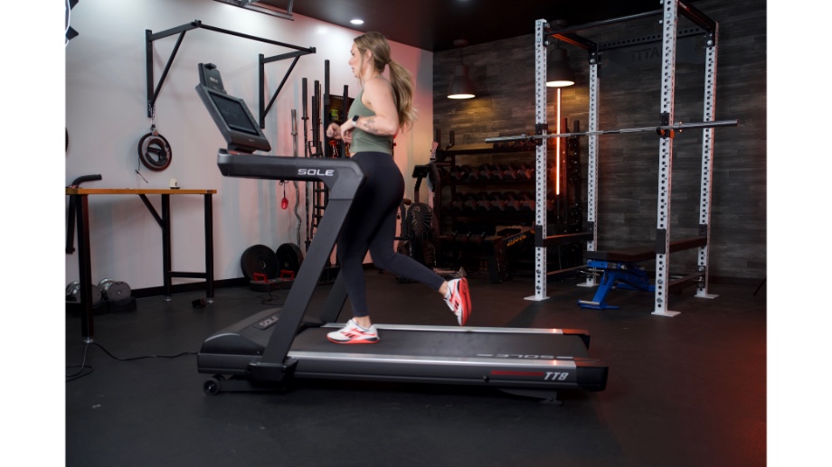 full side view of woman running on sole fitness tt8 treadmill