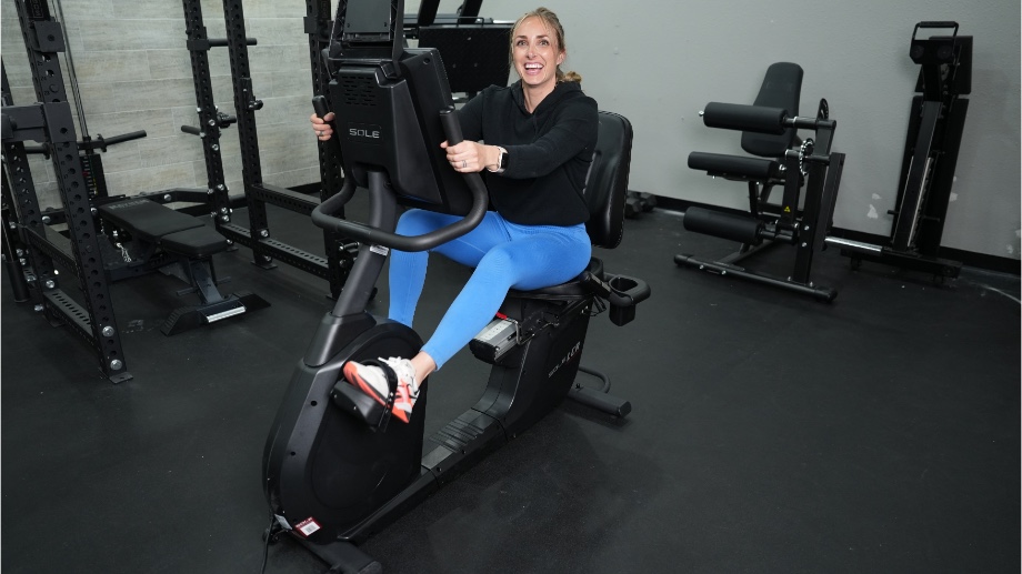 A person smiling while riding the Sole LCR Recumbent Bike.