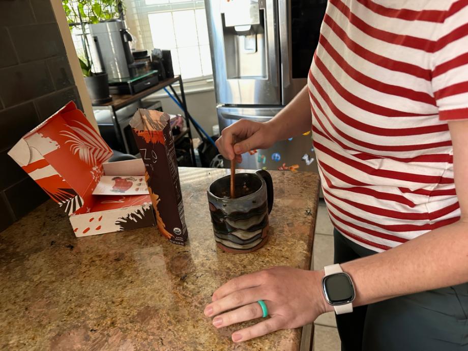 A person stirs a cup of RYZE Mushroom Coffee.