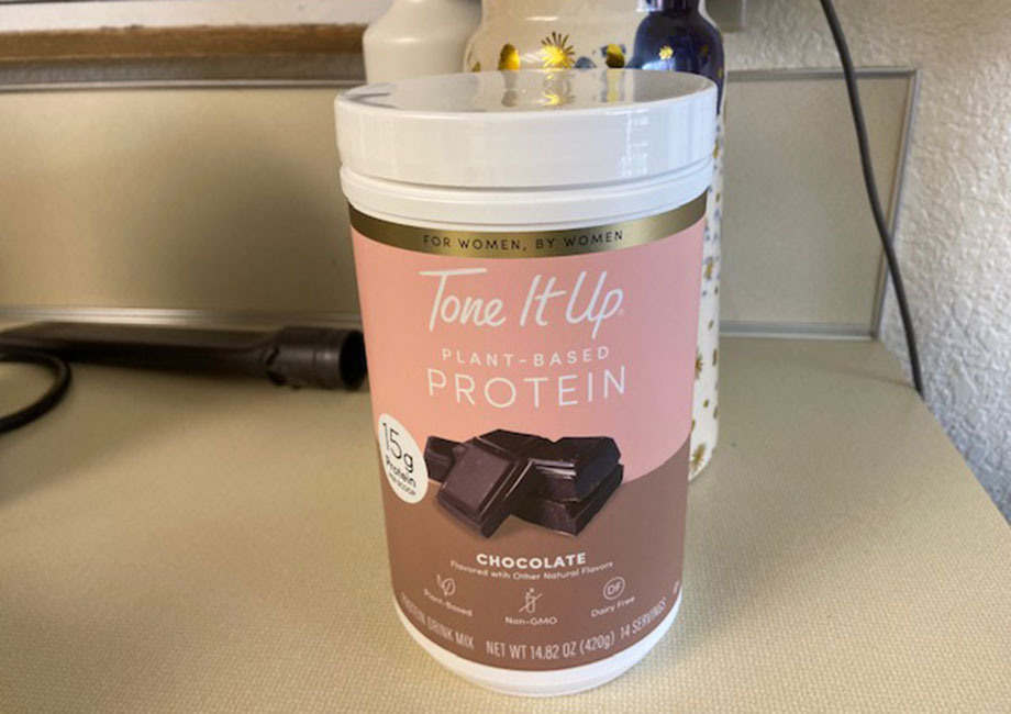 A container of Tone It Up Protein is on a kitchen counter.