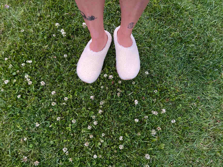 A person wears Topo Revive Recovery clogs in grass.