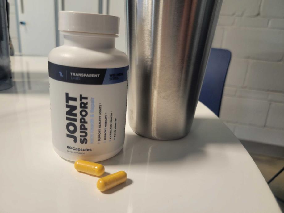 A bottle of Transparent Labs Joint Support next to a few capsules on a kitchen counter.