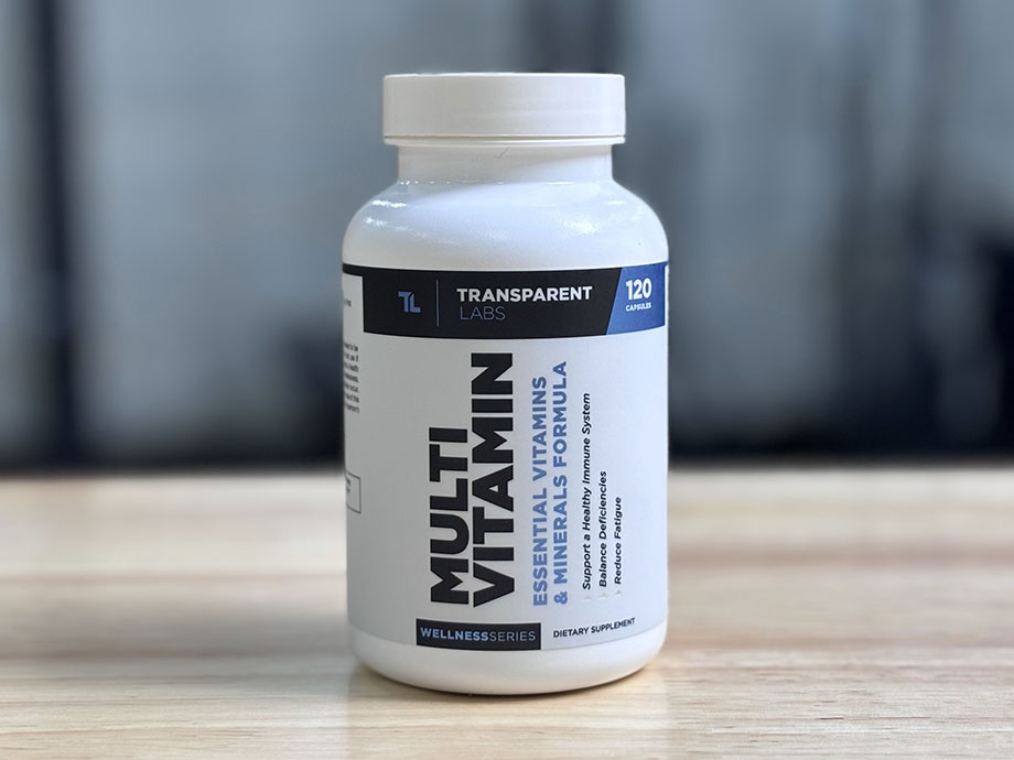 A bottle of Transparent Labs Multivitamin on a table with a blurry gray background