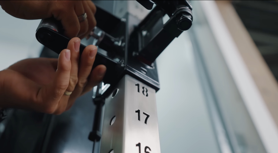 Close-up shot of a man adjusting the height of the trolleys on the REP Arcadia Max functional trainer