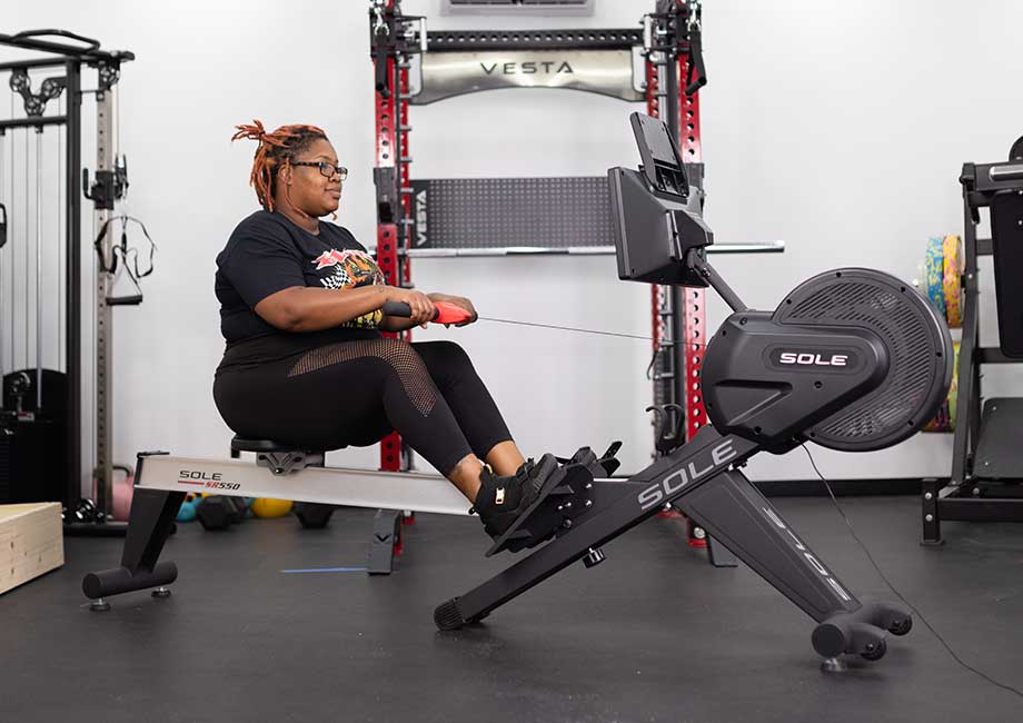 Woman in a gym setting using a Sole SR 550 rowing machine