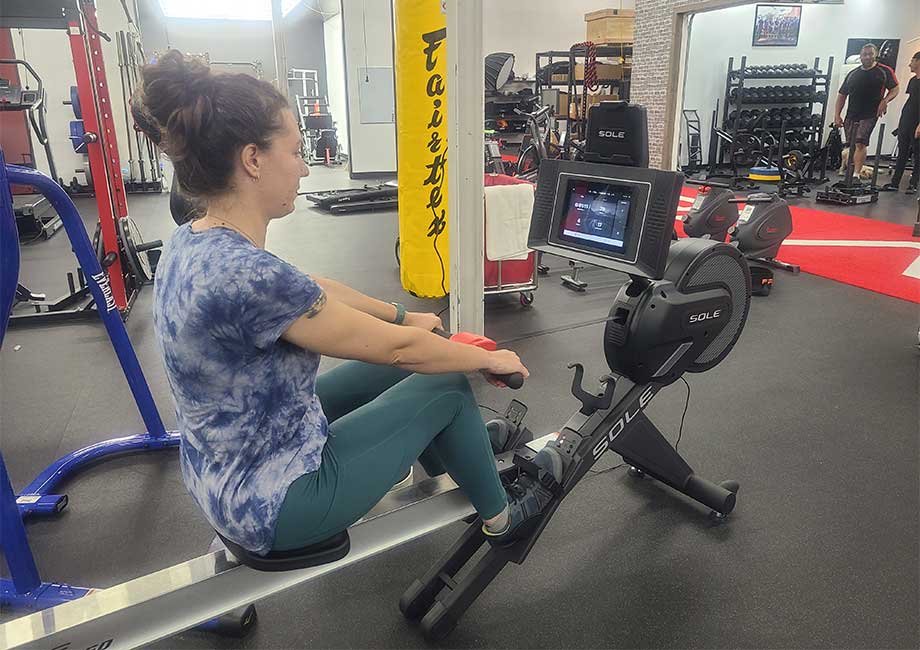 Woman in a gym setting rowing on the Sole SR550 rower