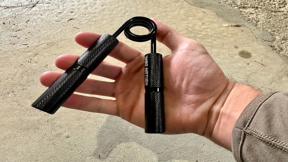 A person holding a WOD Nation Hand Grip Strengthener 