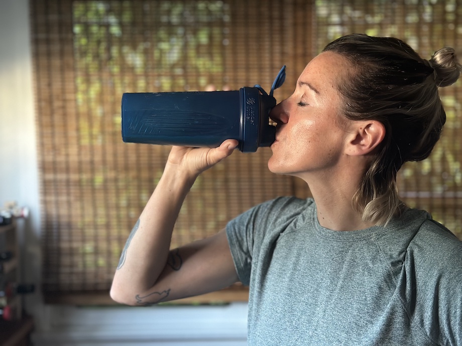 An image of a woman drinking 1st phorm collagen out of a shaker