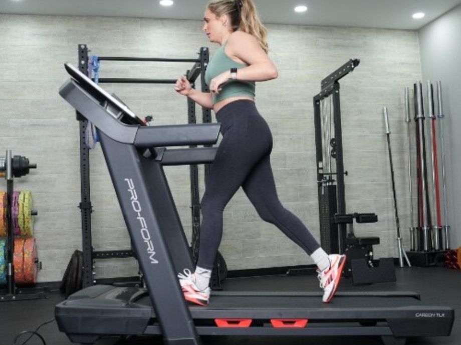 A full side view of a woman jogging on the ProForm Carbon TLX treadmill