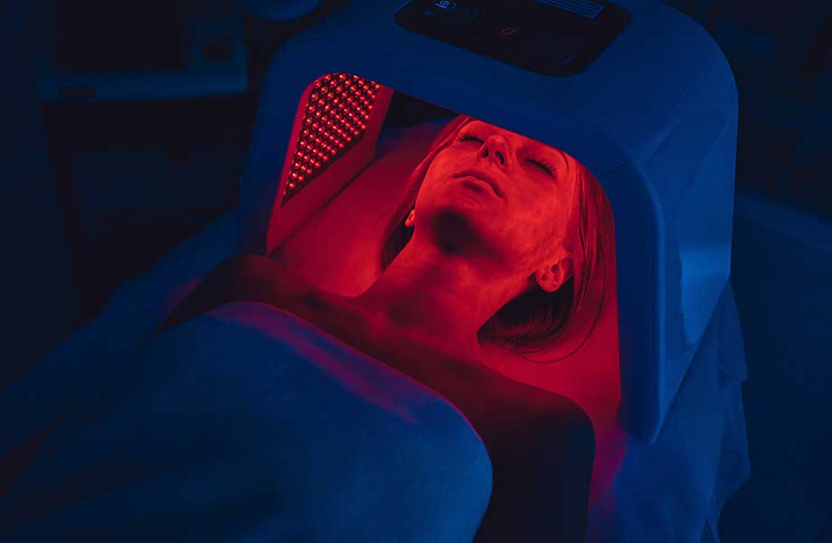 Woman using red light therapy device.