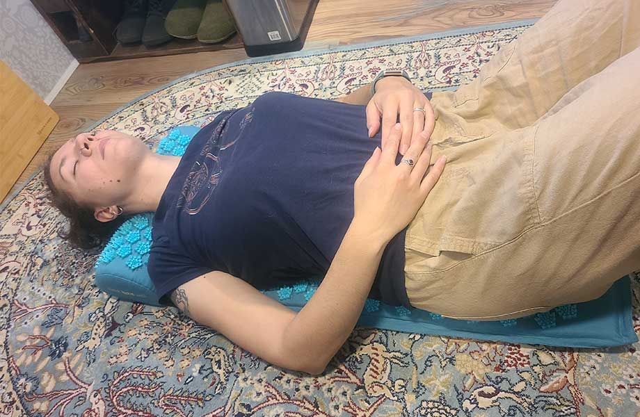 Woman using a TimeBeeWell Acupressure Mat